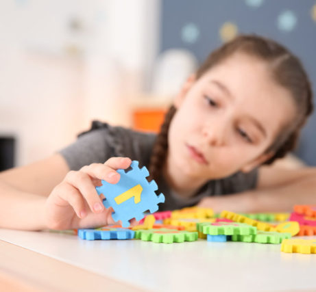 Little girl with autistic disorder playing at home, closeup of puzzles