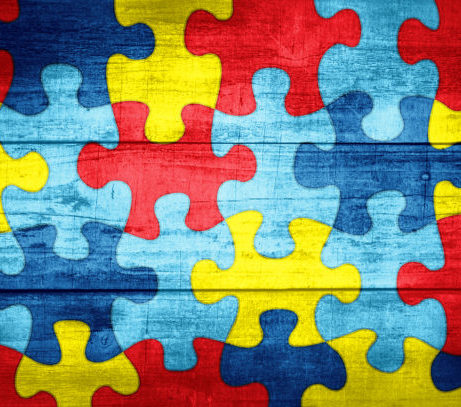 A colorful autism awareness puzzle background with wood texture illustration.